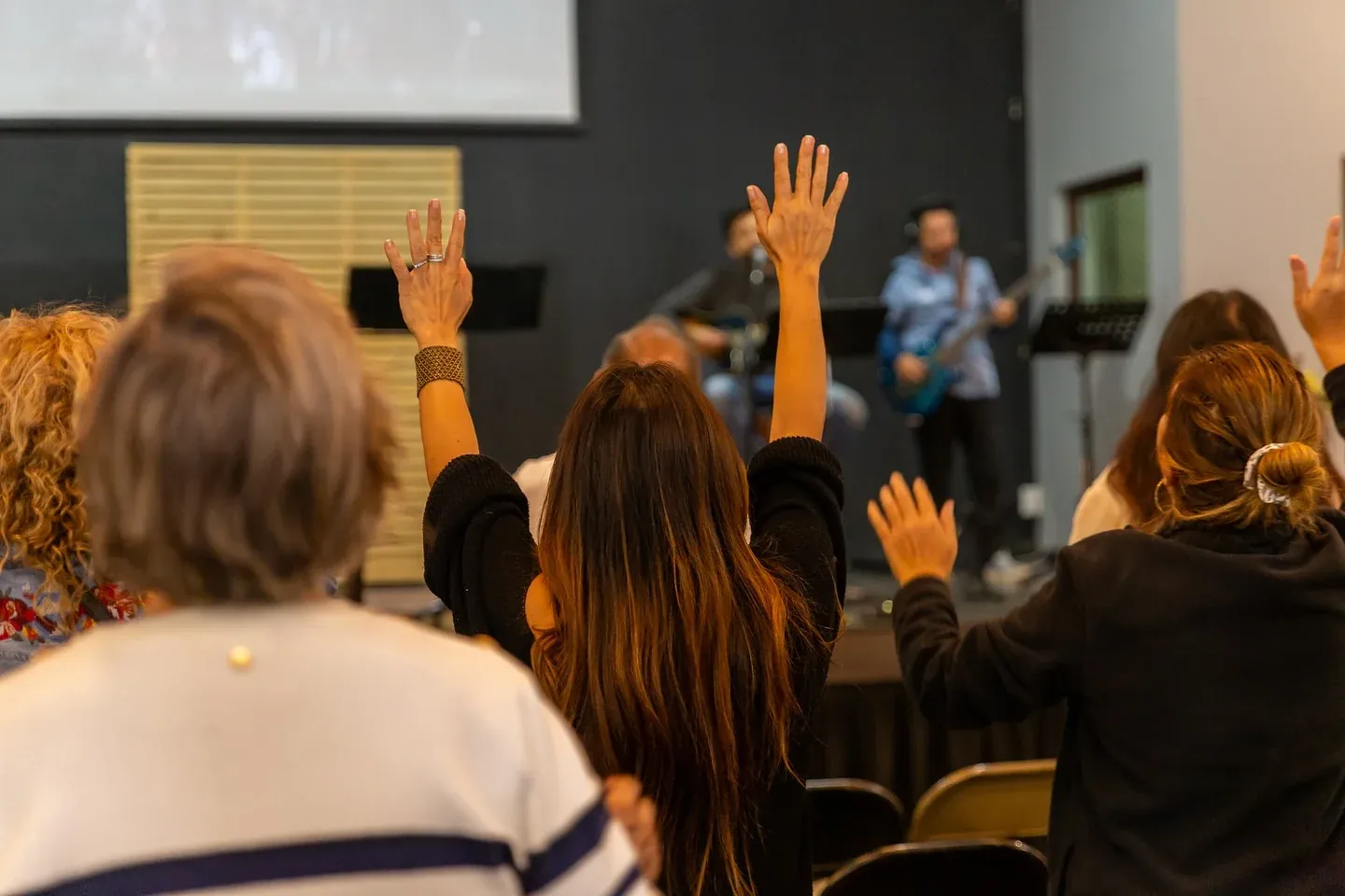 Personas adorando con las manos en alto durante un culto en ICI Oriente